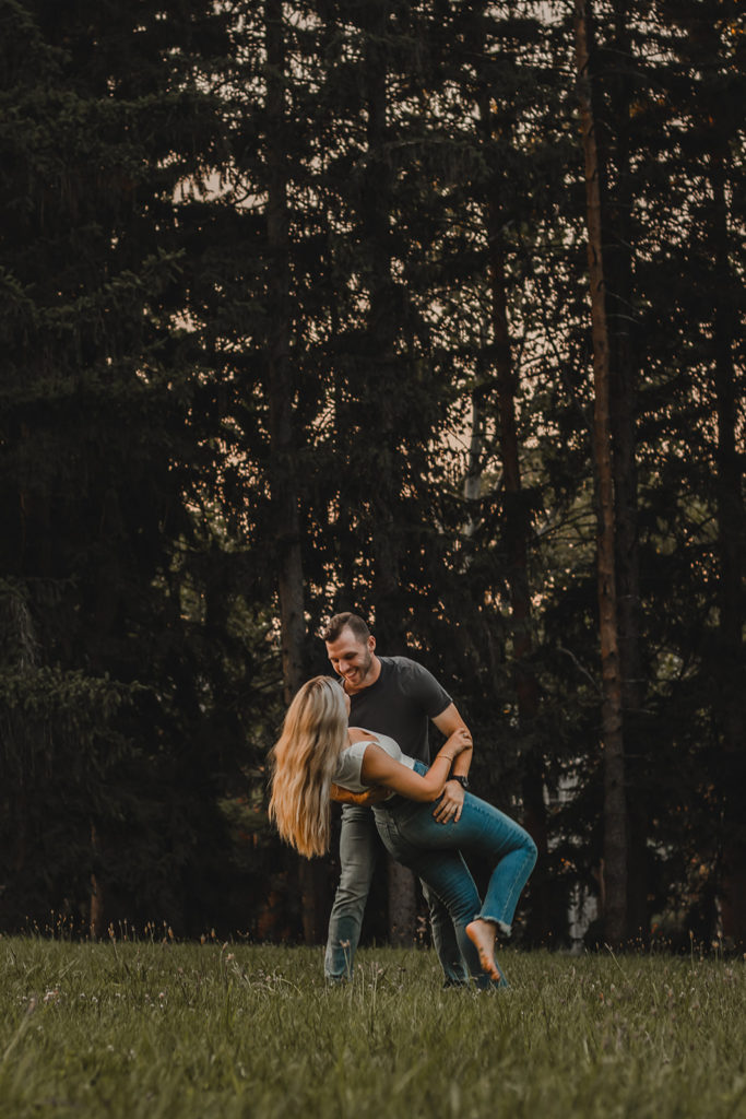 Young man dips his fiance and laughs while leaning in close.