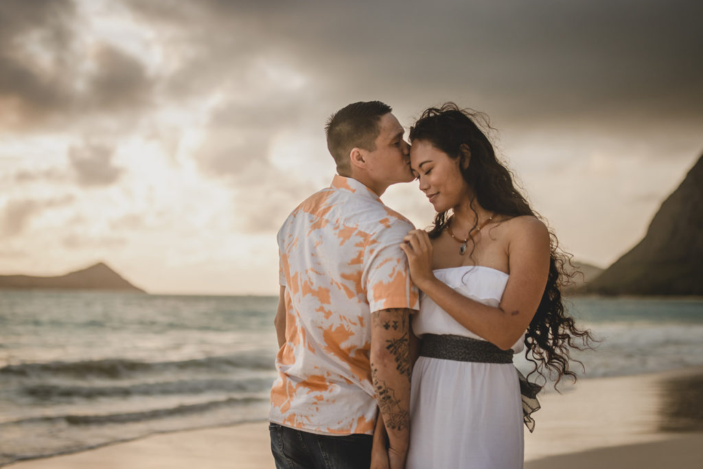 Couple posing in front of ocean in Hawaii. 