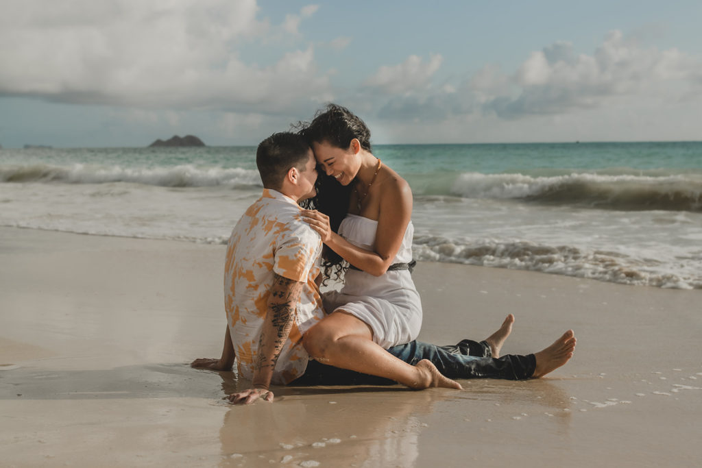 Young engaged couple in surf on a tropical beach.