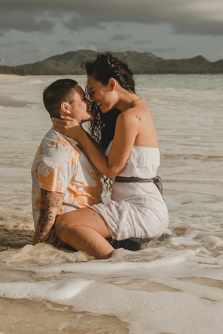 Young engaged couple in surf on the beach.