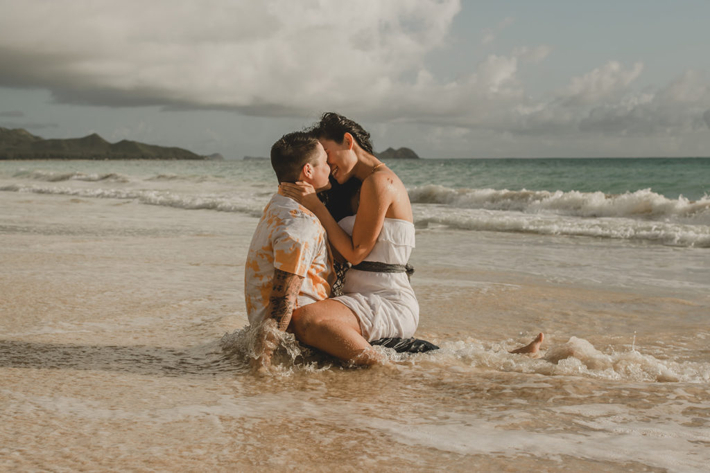 Young engaged couple in surf on the beach kissig.