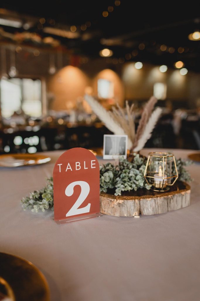 table center pieces for a wedding reception with table number, flowers, and candles