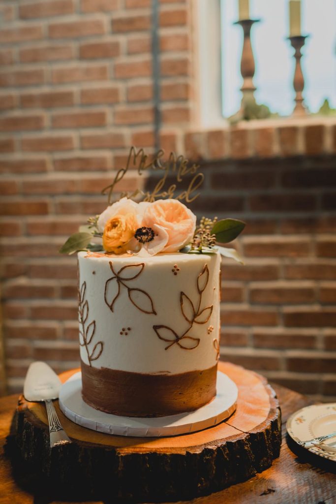 white and gold wedding cake with pink flowers on a wooden table