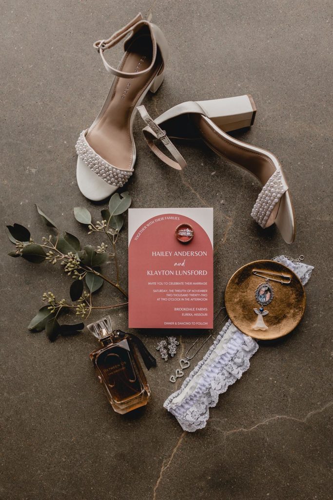 Wedding detail shot including salmon stationary, engagement rings, and shoes