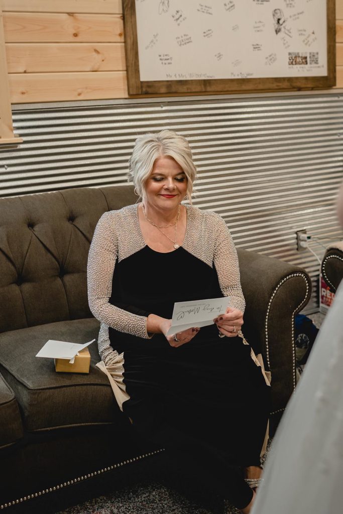 Mother of the bride opening a wedding day present from her daughter on a couch