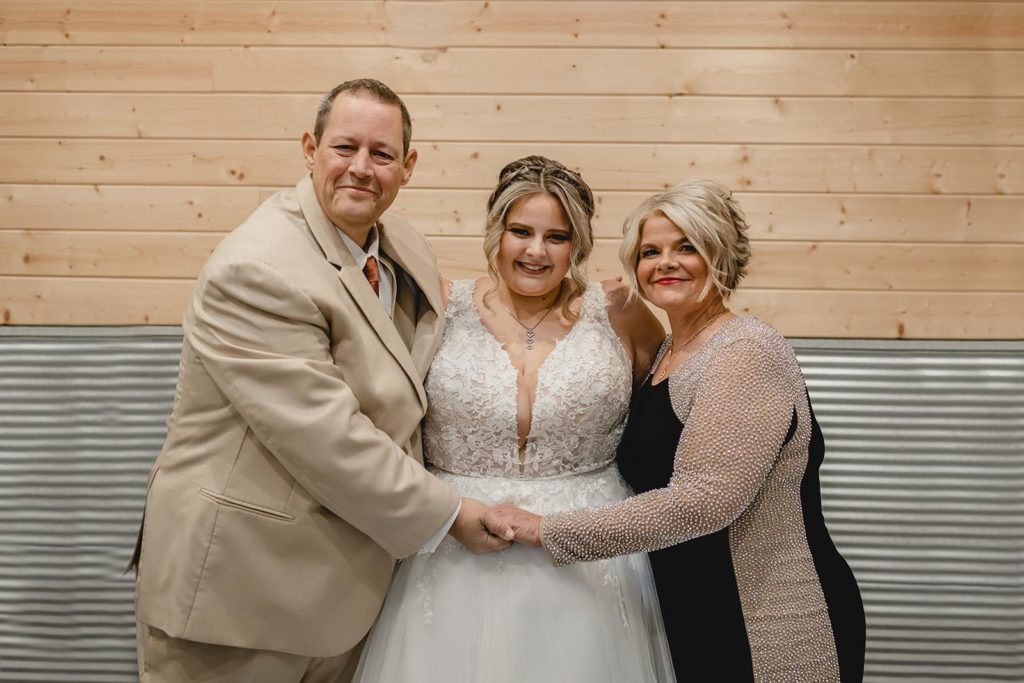 Bride and her parents hugging and smiling
