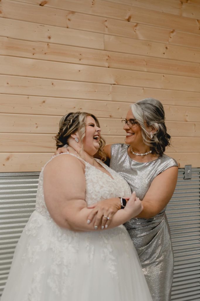 Bride and her new mother-in-law hugging and laughing