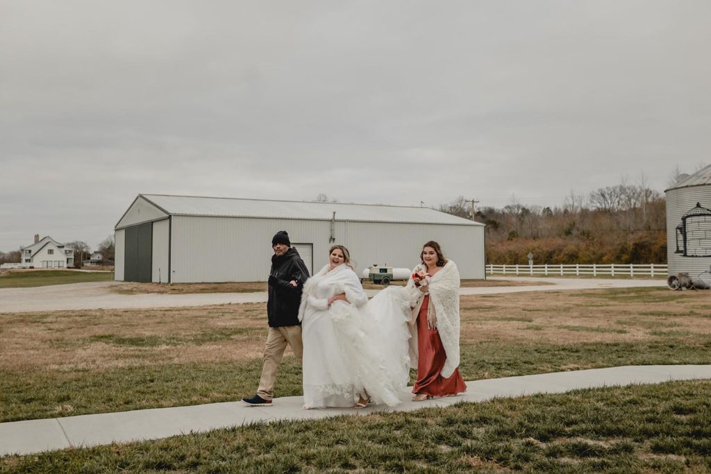 Bride walking outside infront of a barn with her maid of honor