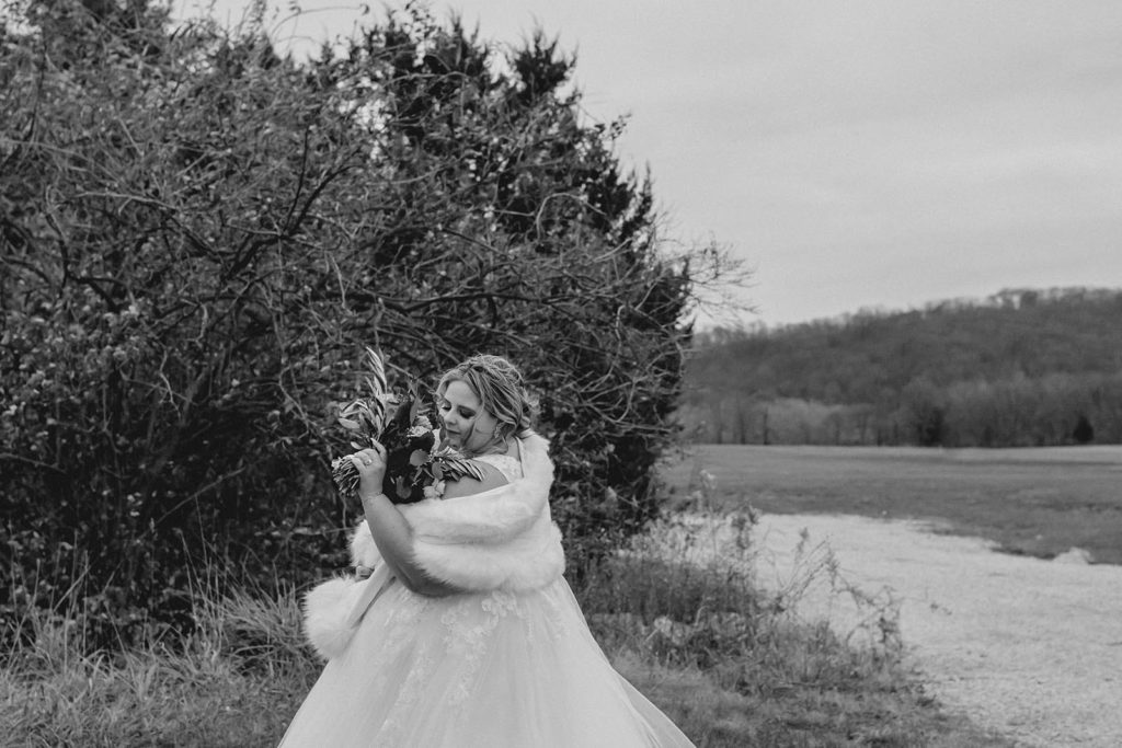 Bride smelling flowers in front of a tree