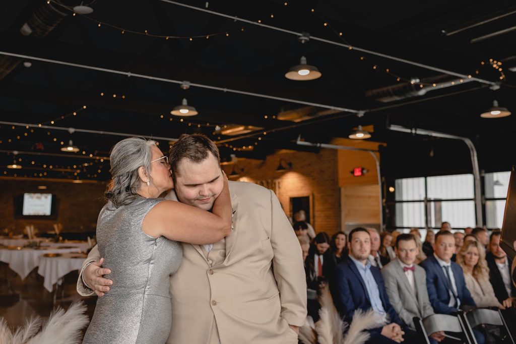 Mother and groom hugging at wedding ceremony