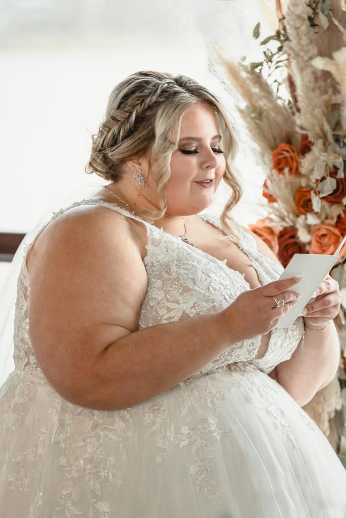Bride reading vows from small white book 