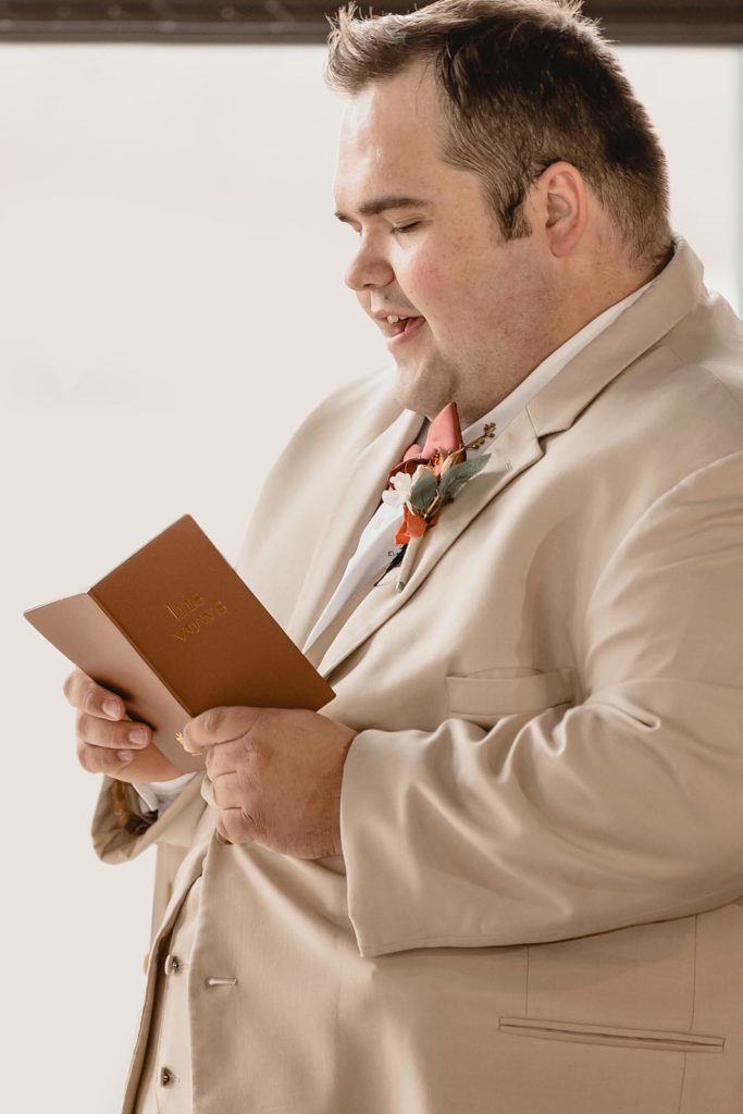 Groom reading wedding vows from small brown book