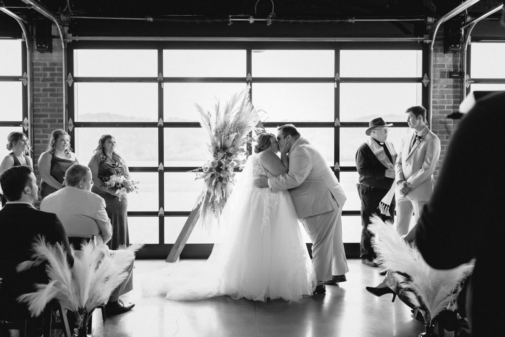 Bride and groom first kiss at alter during wedding ceremony