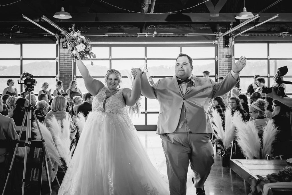 Bride and groom celebrating while walking down aisle after their wedding ceremony