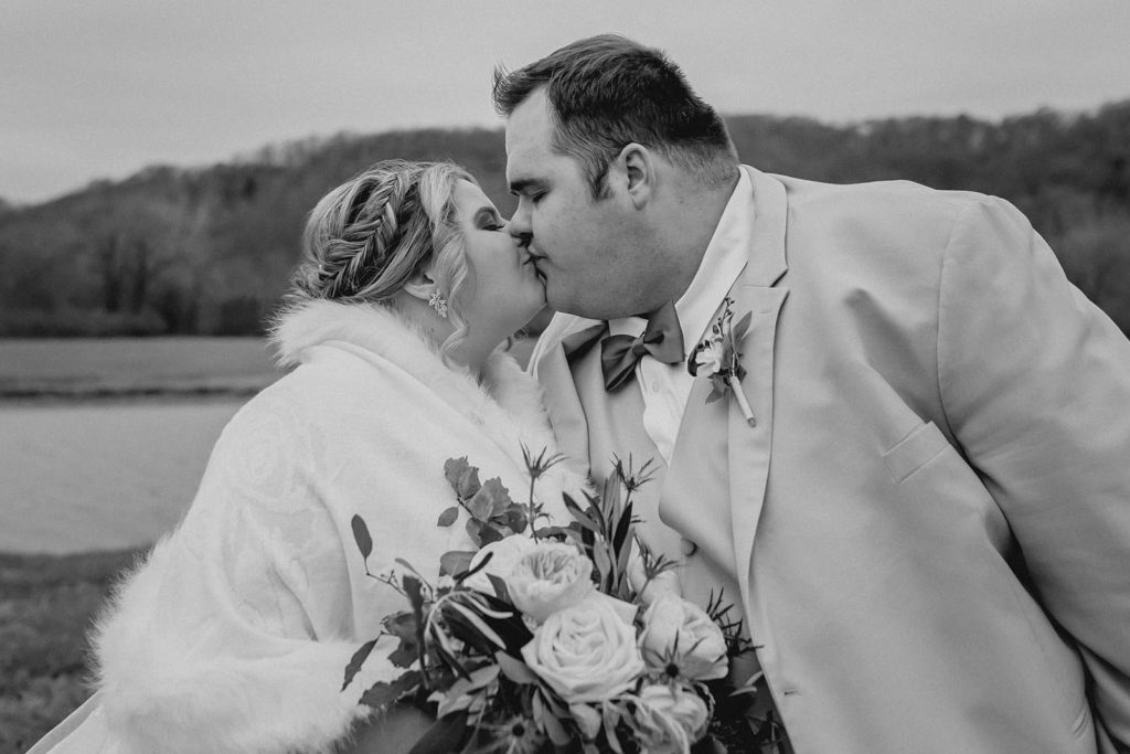 Bride and groom kissing in front of pond