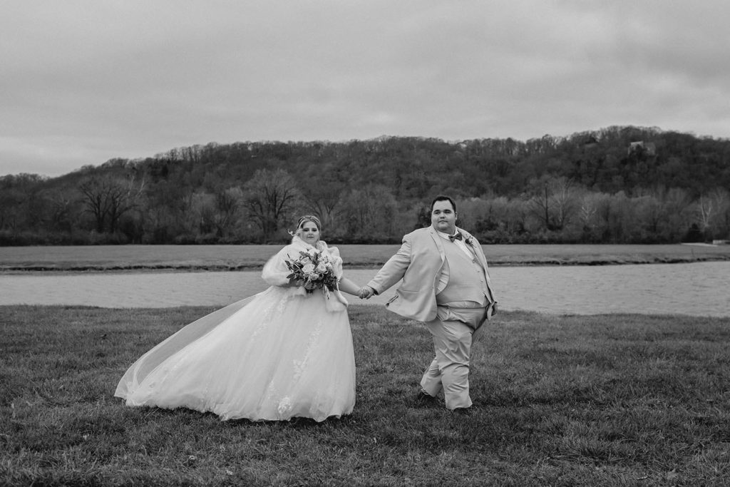 Bride and groom walking in front of lake 