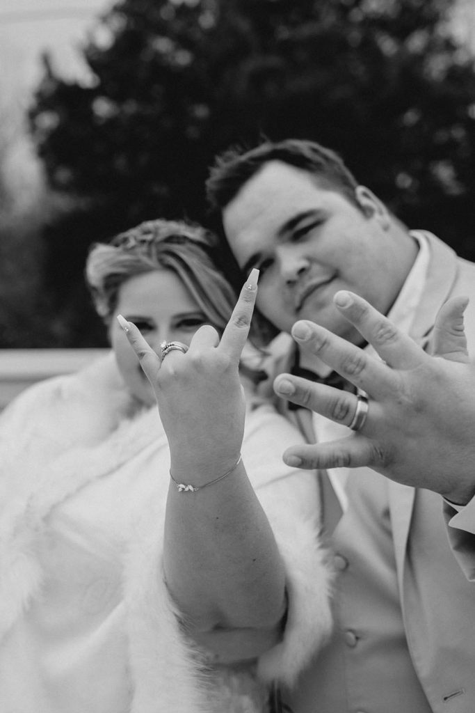 Bride and groom showing off their rings to the camera