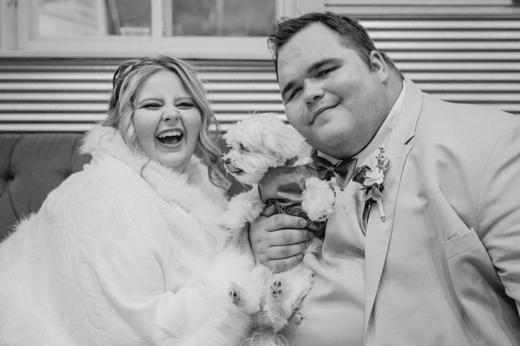 Bride groom and their white dog posing on a couch