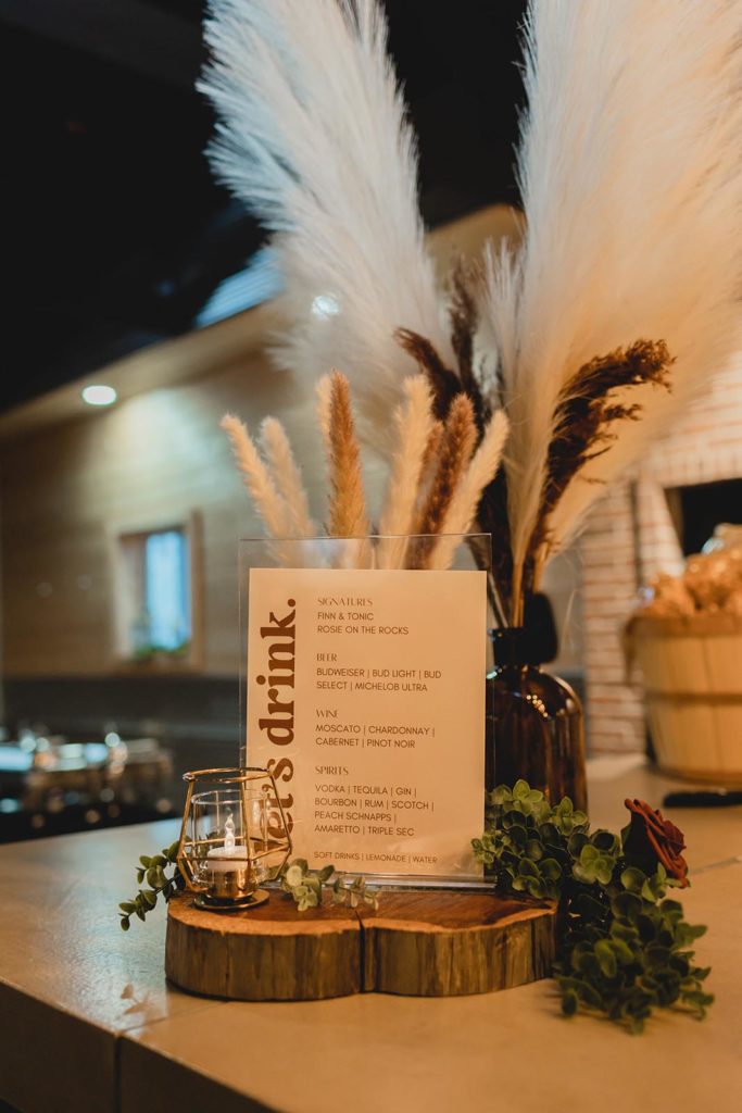 Signature drink sign sitting on wooden slab with large feathers