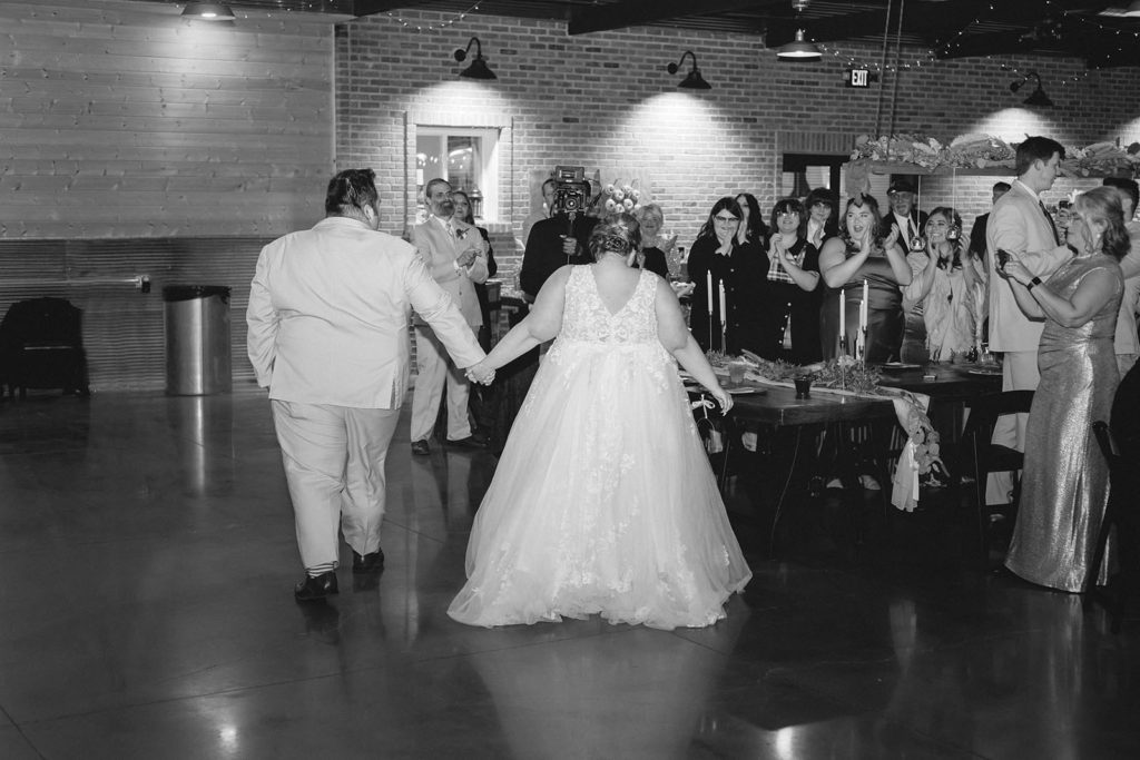Bride and groom entering wedding reception holding hands