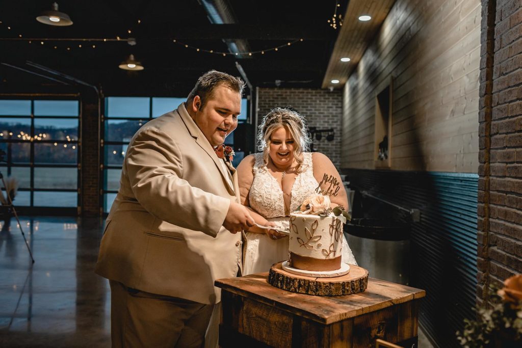 Bride and groom cutting white and gold wedding cake