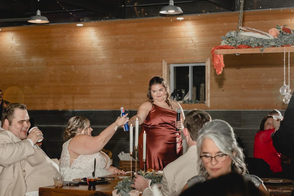 Maid of honor toasting with bride during wedding reception speech