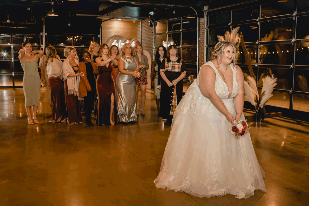 Bride tossing bouquet of flowers and celebrating with her guests