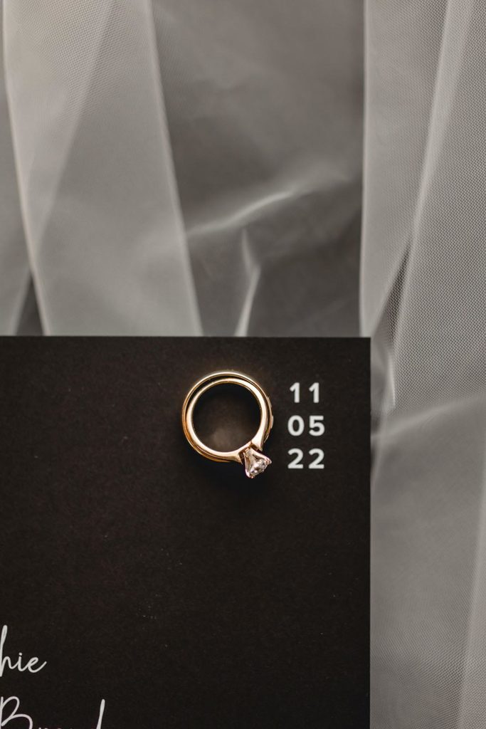 Wedding ring and engagement ring placed on wedding invitaiton
