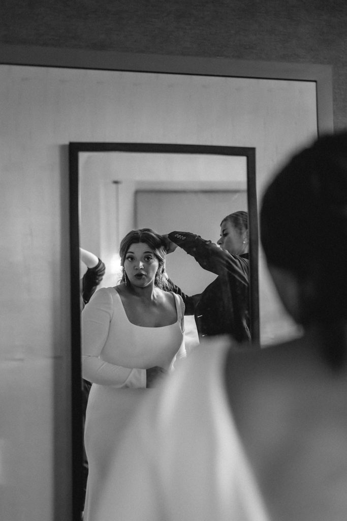 Black and white photo of bride getting her hair done on wedding day.