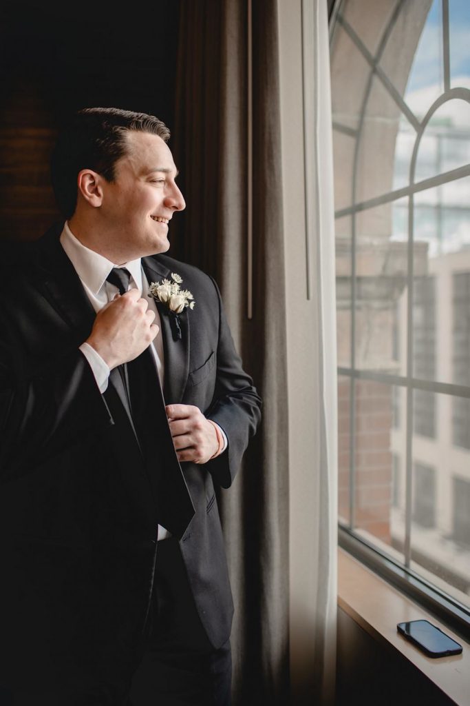 Grome getting ready on wedding day infront of large window