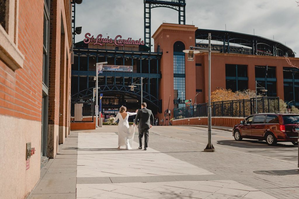 Bride and groom walking infront of Busch Stadium