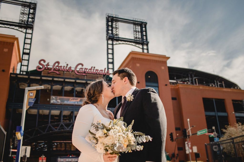 Bride and groom kissing infront of busch stadium on wedding day