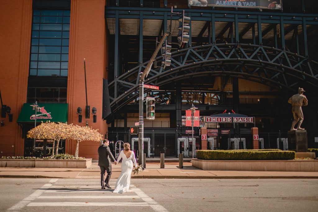Bride and groom cossing street infront of busch stadium st. Louis
