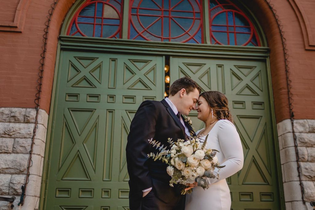 Bride and groom posing at Anheiser Busch Brewery with large green door