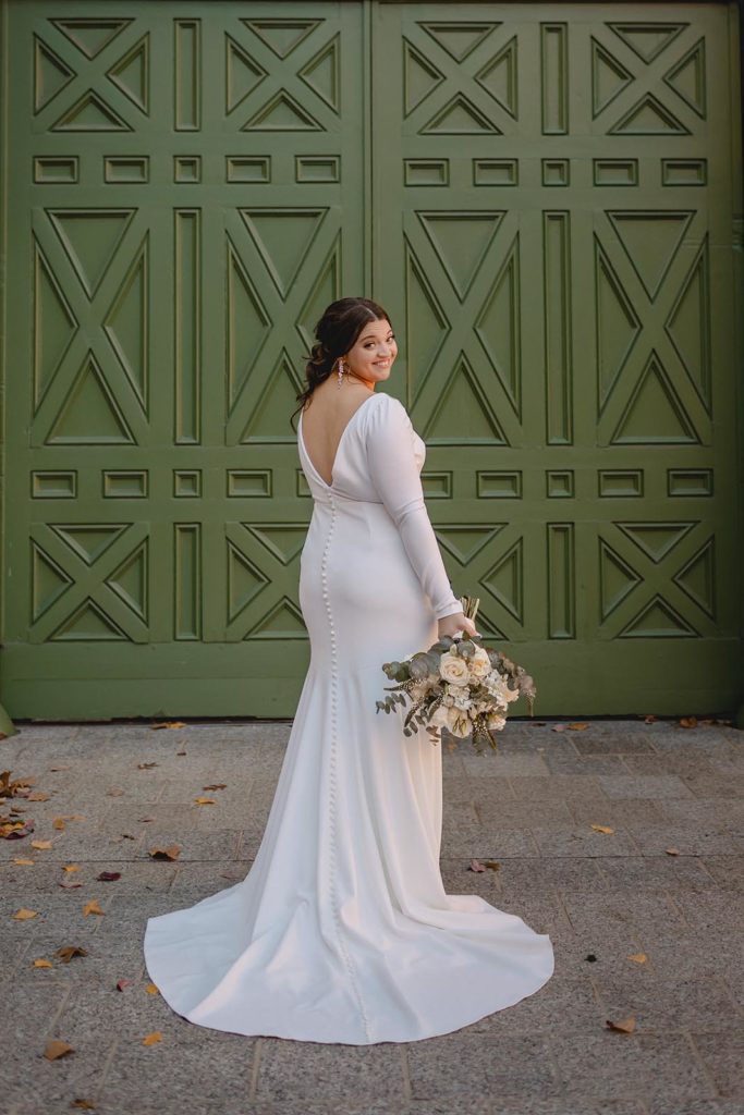 Bride posing at Anheiser Busch Brewery infront of large green door.