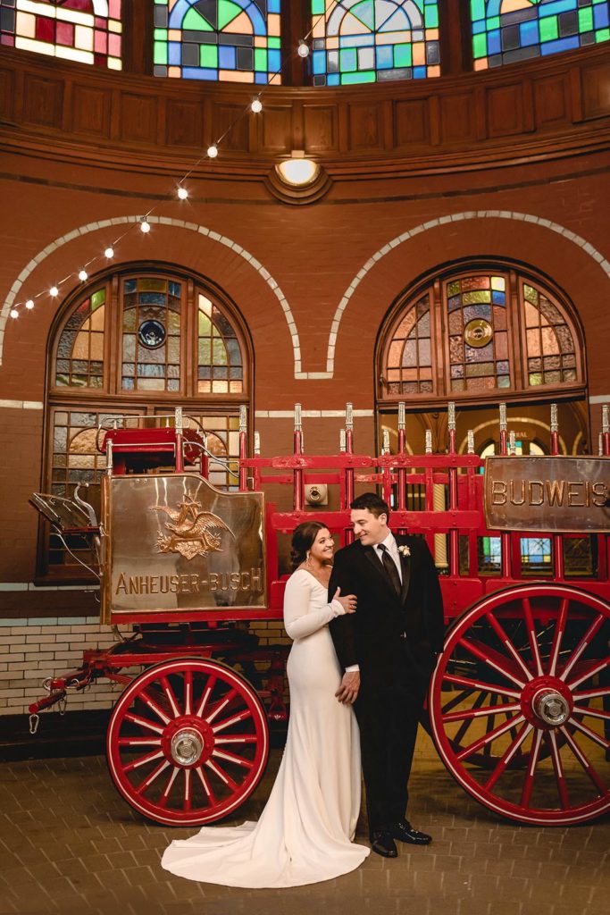 Bride and groom posing infront of Anheuser Busch Wagon