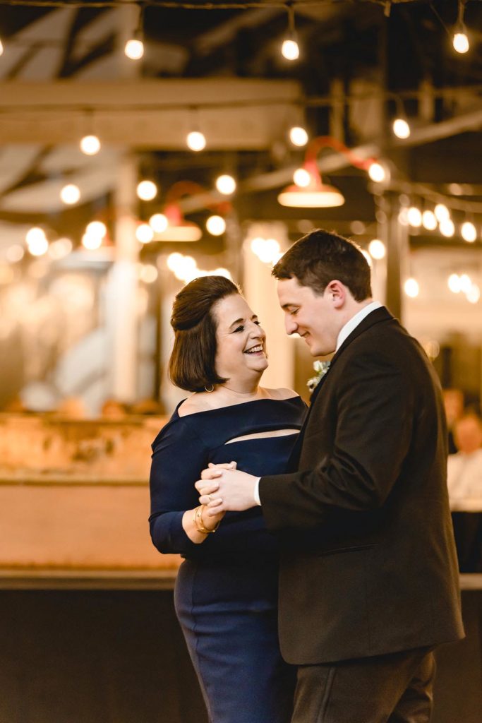 Groom and mother first dance under string lights at STL Brewery 