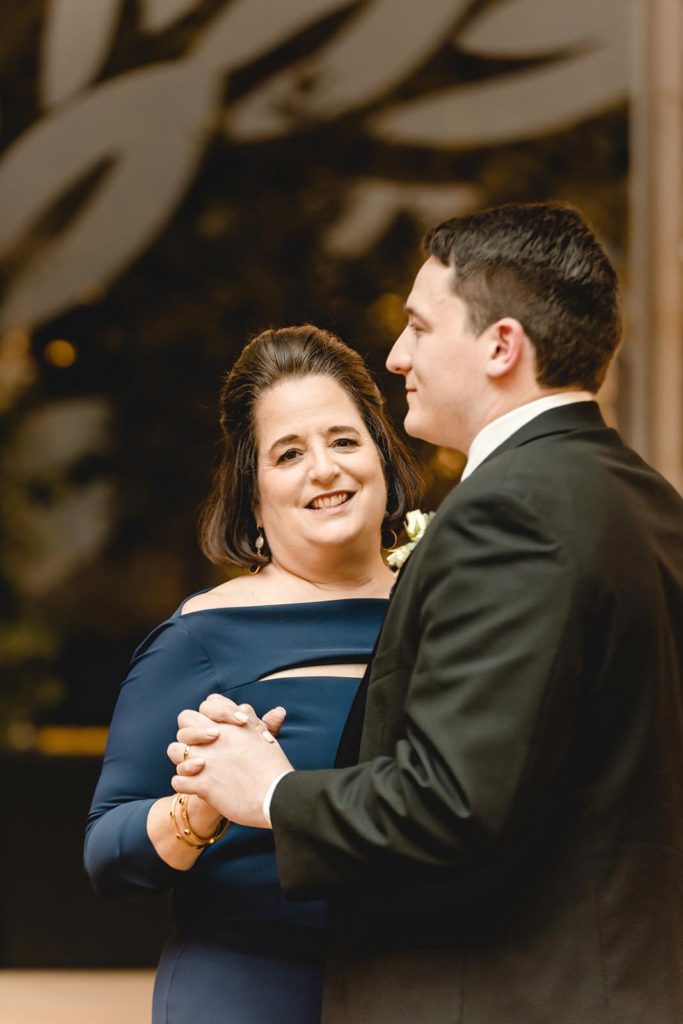 Groom and mother first dance under string lights at STL Brewery