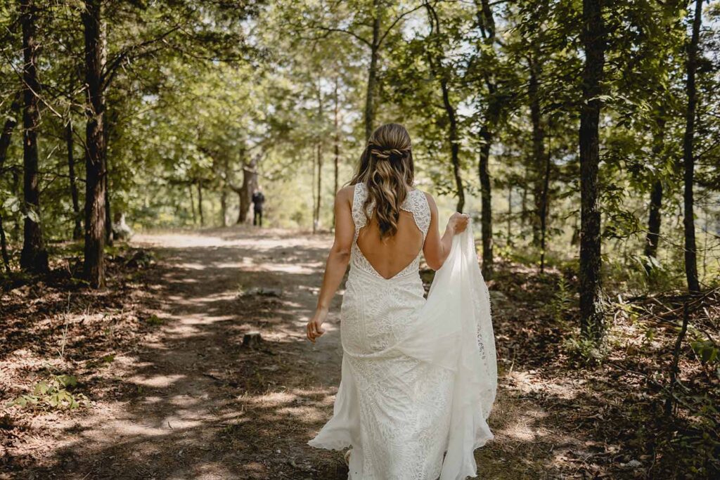 bride hikes through green covered forest to meet groom for first look