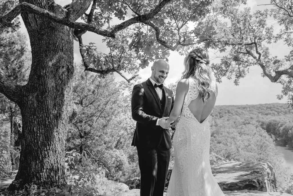 black and white shot of groom smiling at his bride after their first look on Lost Hill Lake's Thinking Rock scenic overlook