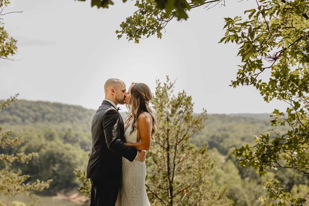 Boho bride and groom kiss on scenic overlook