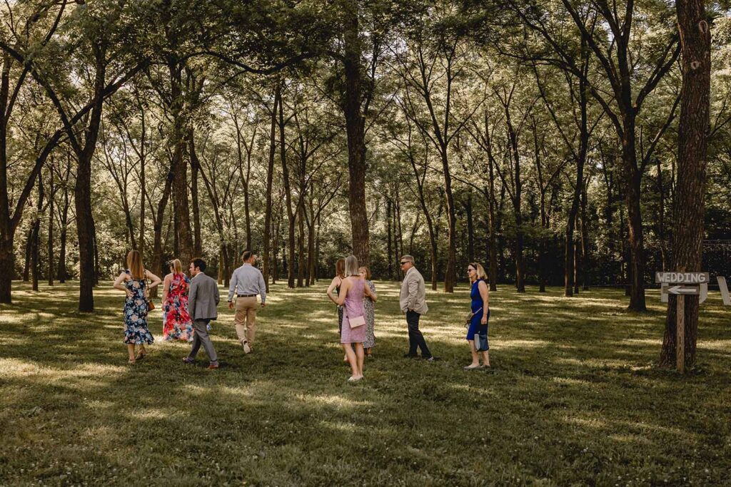 A group of guests walking through the trees to ceremony space in Walnut Grove at Lost Hill Lake