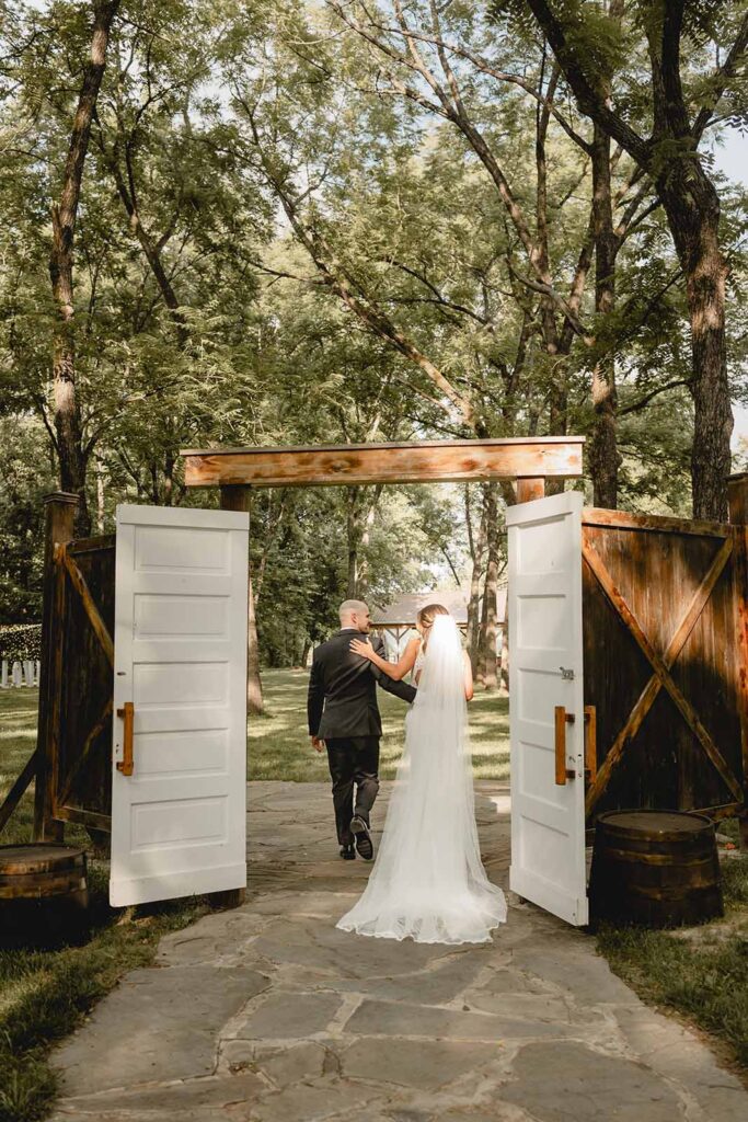 Candid shot from behind of the bride and groom holding each other's backs as they walk through the doors at end of the aisle after their ceremony