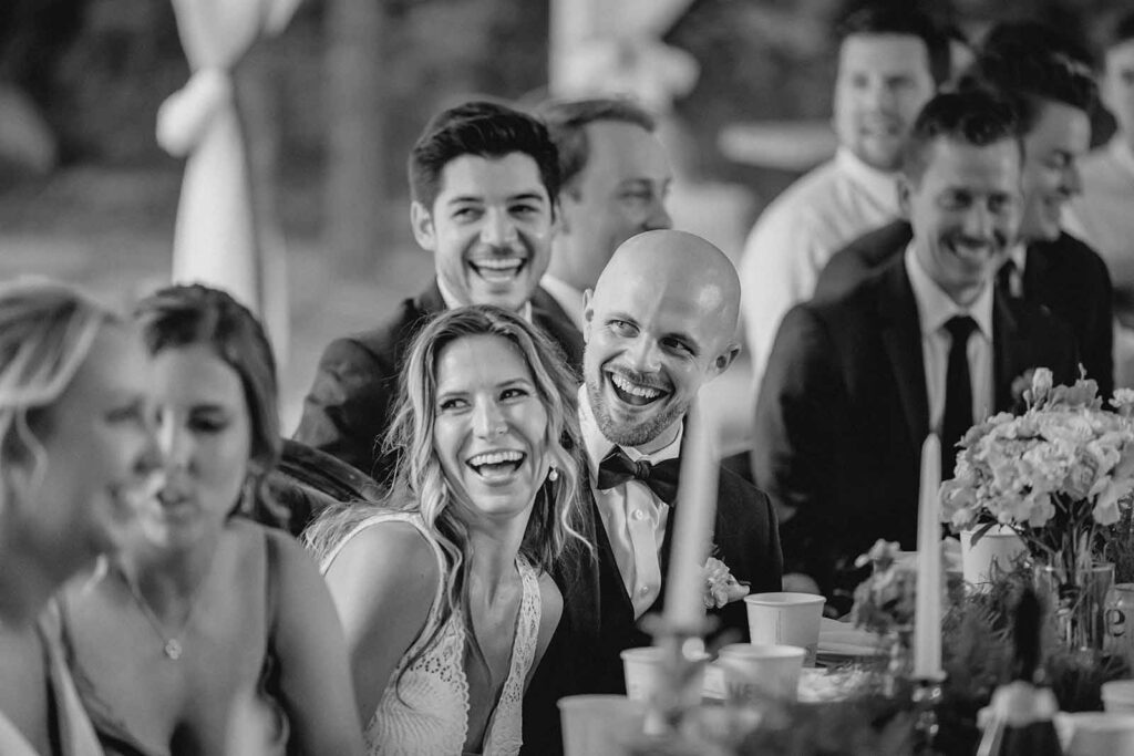 Black and white shot of bride and groom laughing in response to wedding toast