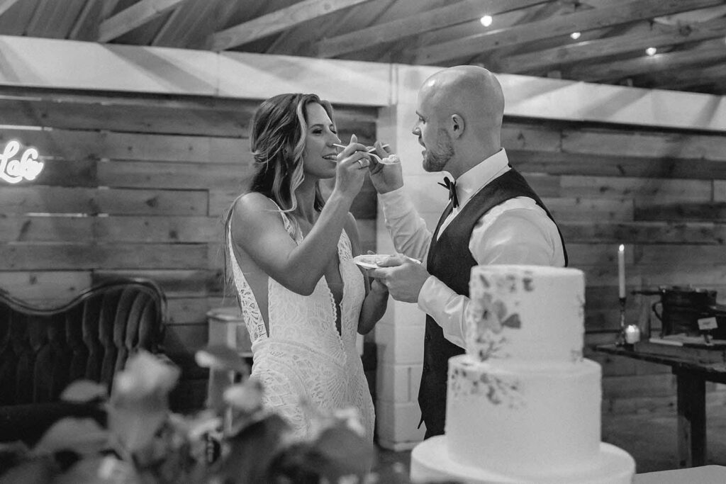 Black and white of bride and groom feeding each other bit of wedding cake