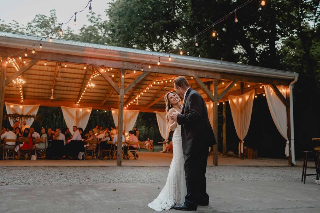 Bride and her father holding hands and swaying during their first dance outside during blue hour
