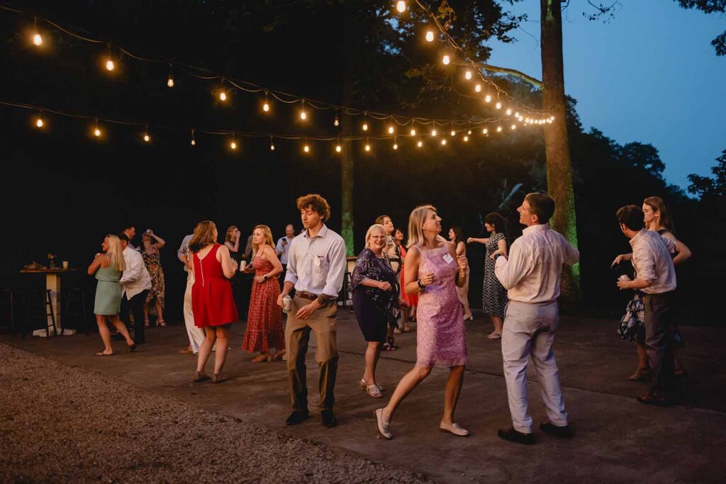 Wedding guests dance on the outdoor dance floor under strands of string lights