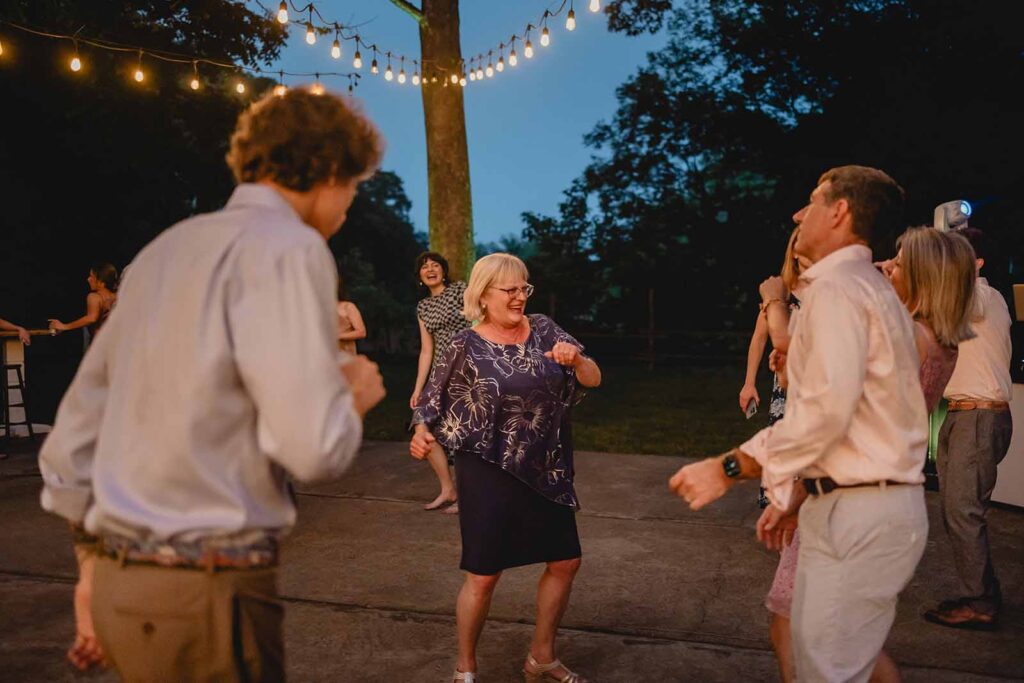 Wedding guests dancing  outdoor dance floor under strands of string lights
