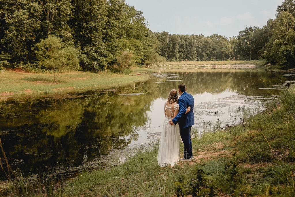 behind a bride and groom looking out over a small lake at Quail Ridge Park