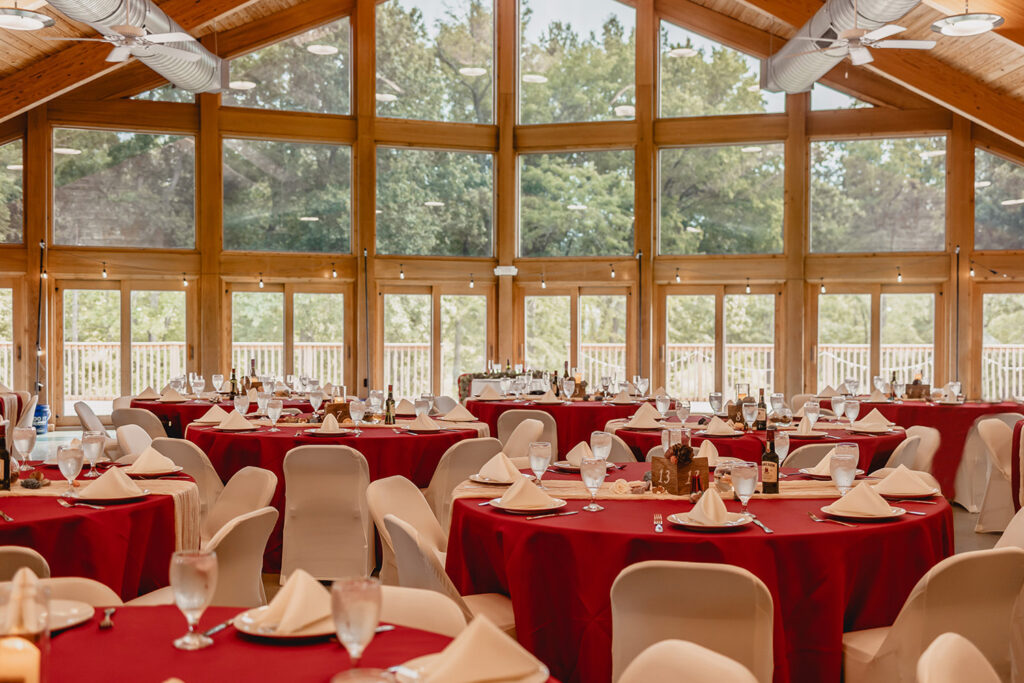 Interior shot of Quail Ridge Lodge set up for wedding reception with burgundy round tablecloths and white chairs